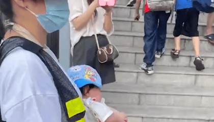 家长抱婴儿站校门口执勤，教育局：自愿参与